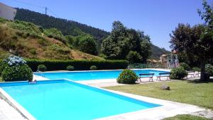 a large blue swimming pool with a hill in the background at Casa do Limoeiro 1 in Valezim