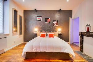 a bedroom with a bed with two orange pillows at Sous le Charme de Charles Sauna & Jacuzzi Nancy in Nancy