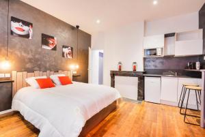 a bedroom with a large white bed and a kitchen at Sous le Charme de Charles Sauna & Jacuzzi Nancy in Nancy