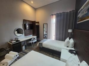 ein Hotelzimmer mit zwei Betten und einem Schreibtisch in der Unterkunft Kathu Hotel in Kathu
