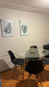 een eetkamer met een glazen tafel en stoelen bij COMODA Y HERMOSA CABAÑA DE 2 dormitorios in Temuco +3 foto's