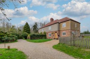 an old brick house with a fence and a gravel driveway at Keepers Cottage in Sall