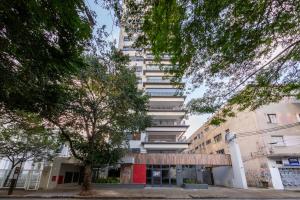 a tall white building with trees in front of it at B Homy Librio in São Paulo
