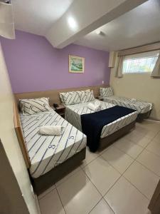 two beds in a room with purple walls at Hotel Stela - A 2 min do Metrô Paraíso e Poucos Passos da Av Paulista in São Paulo