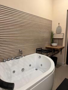 une grande baignoire blanche dans une pièce avec un mur en bois dans l'établissement Urban SPA Loft, à Golčŭv Jeníkov