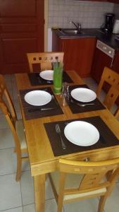 a wooden table with white plates on top of it at Le Roi du Sundgau près de la Horse - Mooslargue in Mooslargue