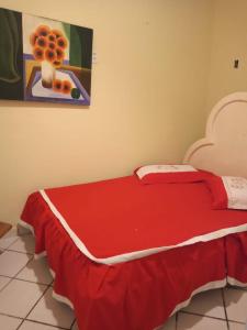 a bedroom with a red bed with a picture on the wall at Casa princesa isabel in Porto Seguro