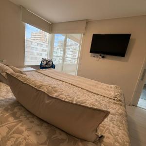 a bedroom with a large bed with a flat screen tv at Departamento en Viña del mar cercano a playa, casino de juegos, mall in Viña del Mar