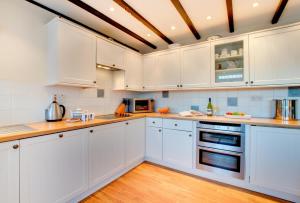 a white kitchen with white cabinets and wooden floors at Castle Point Cottage Craster in Craster +9 photos