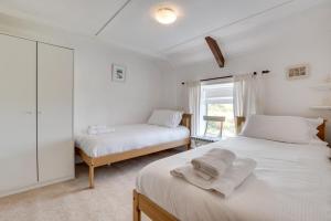 a white bedroom with two beds and a window at Castle Point Cottage Craster in Craster