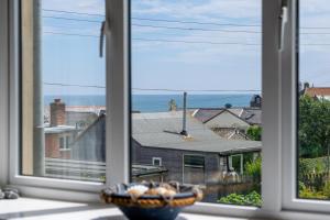 a window with a view of a house and the ocean at Castle Point Cottage Craster in Craster