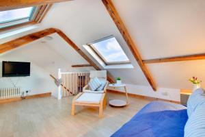 a attic living room with a bed and a tv at Castle Point Cottage Craster in Craster
