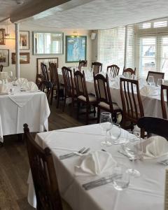a dining room with tables and chairs with white tablecloths at Noble Goose Rooms in Coggeshall