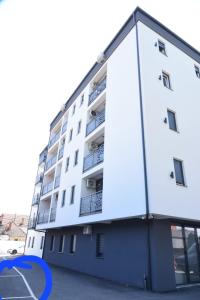 a white apartment building with a blue circle next to it at L&L Apartman in Smederevska Palanka