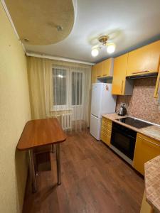 a kitchen with a wooden table and a white refrigerator at Apart Center in Sumy