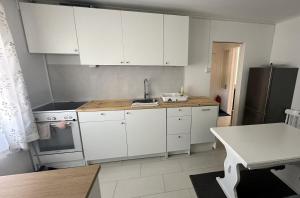 a kitchen with white cabinets and a sink and a refrigerator at Koselig 3 roms leilighet på Rjukan in Øverland