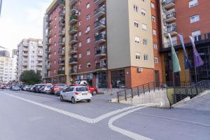 a white car parked in a parking lot next to buildings at Infinit Apartment in Prishtinë