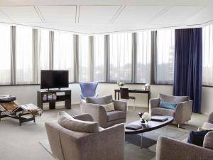 a living room with couches and chairs and a tv at Sofitel Brussels Europe in Brussels
