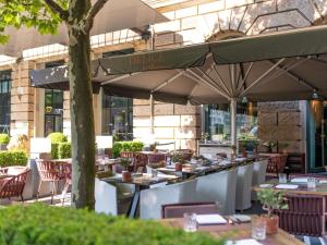 a restaurant with tables and chairs with umbrellas at Sofitel Munich Bayerpost in Munich