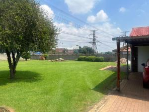 a green yard with a tree and a house at Clear Skies in Kempton Park
