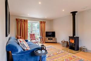 a living room with a blue couch and a fireplace at Alcocks Cottage in Syderstone