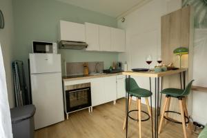 a kitchen with white cabinets and green bar stools at Jungle Studio - Déco tropicale et confort moderne in Montoir-de-Bretagne