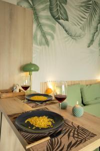 a table with two glasses of wine and a plate of food at Jungle Studio - Déco tropicale et confort moderne in Montoir-de-Bretagne