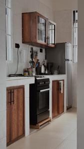a kitchen with a black stove and wooden cabinets at Cocohut Zanzibar - Kendwa & Nungwi in Kendwa