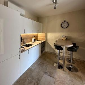 a kitchen with white cabinets and a table with stools at Spacieux T3 en duplex rénové avec terrasse in Saint-Rémy-de-Provence
