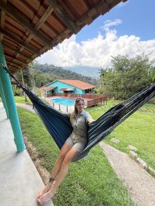 una donna è seduta su un'amaca vicino a una piscina di Bike Mantiqueira hospedagem e camping a Queluz Altre 27 foto