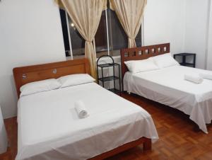 a bedroom with two beds with white sheets at Refugio de Daye in Puerto Ayora