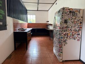una cocina con nevera con pegatinas. en Bioluminiscencia Hostel Tours Santa Teresa, en Santa Teresa Beach