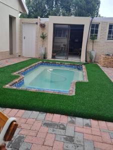 a swimming pool in a yard with green grass at Vuurpyl Accommodation in Klerksdorp
