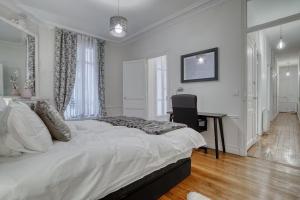 una camera da letto bianca con un letto grande e una scrivania di 120 m2 Luxury Eiffel Signature a Parigi