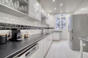 una grande cucina con armadi bianchi e frigorifero di 120 m2 Luxury Eiffel Signature a Parigi Altre 17 foto
