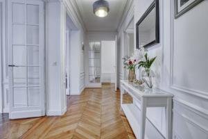 un corridoio con pareti bianche e un tavolo bianco con fiori di 120 m2 Luxury Eiffel Signature a Parigi