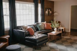 Una sala de estar con un sofá de cuero y una mesa. en Briarwood Cottage Hot Tub Putt Putt Games, en Aiken