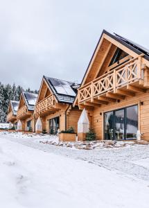 ein großes Holzhaus mit Schnee auf dem Boden in der Unterkunft Domki Osada Zieleniec in Duszniki-Zdrój