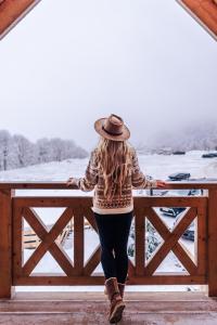 Eine Frau mit Hut steht auf einem Zaun in der Unterkunft Domki Osada Zieleniec in Duszniki-Zdrój