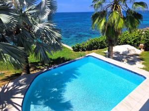 a swimming pool with a view of the ocean at Whispering Clouds Beach House in Kings Pen