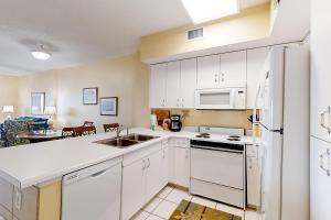 una cocina con armarios blancos y electrodomésticos blancos en Tidewater 608, en Orange Beach