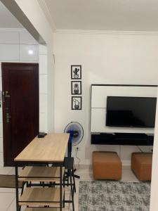 a room with a table and a flat screen tv at Pertinho do mar para relaxar in Água Boa