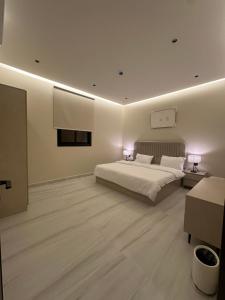 a white bedroom with a bed and two lamps at الواجهة in Buraydah