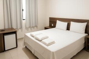 a bedroom with a large bed with white sheets and pillows at Benni Palace Hotel in Parauapebas