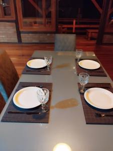 a table with white plates and glasses on it at Recanto Nascer do Sol in Nova Petrópolis