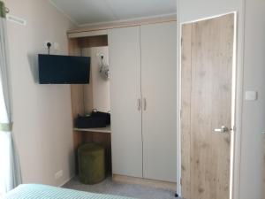 a bedroom with a large white cabinet and a tv at 75 Orchard Mount, 3 bed luxury caravan Skirlington- sleeps 6 in Hornsea