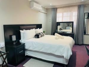 a bedroom with a large white bed and a mirror at Quiet Corner Guest House Kokstad in Kokstad