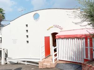 a white building with a red door at トロピカーナ in Fukuyama