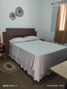 una camera da letto con un grande letto bianco con una finestra di #Canto do Sossego a Caraguatatuba