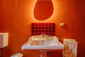 un bagno con un lavandino bianco in una parete arancione di Unique Bologna Penthouse with Frescoes and Charm a Bologna